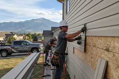 Technicians performing vinyl siding repair on Colorado Springs home with precision tools and new panels